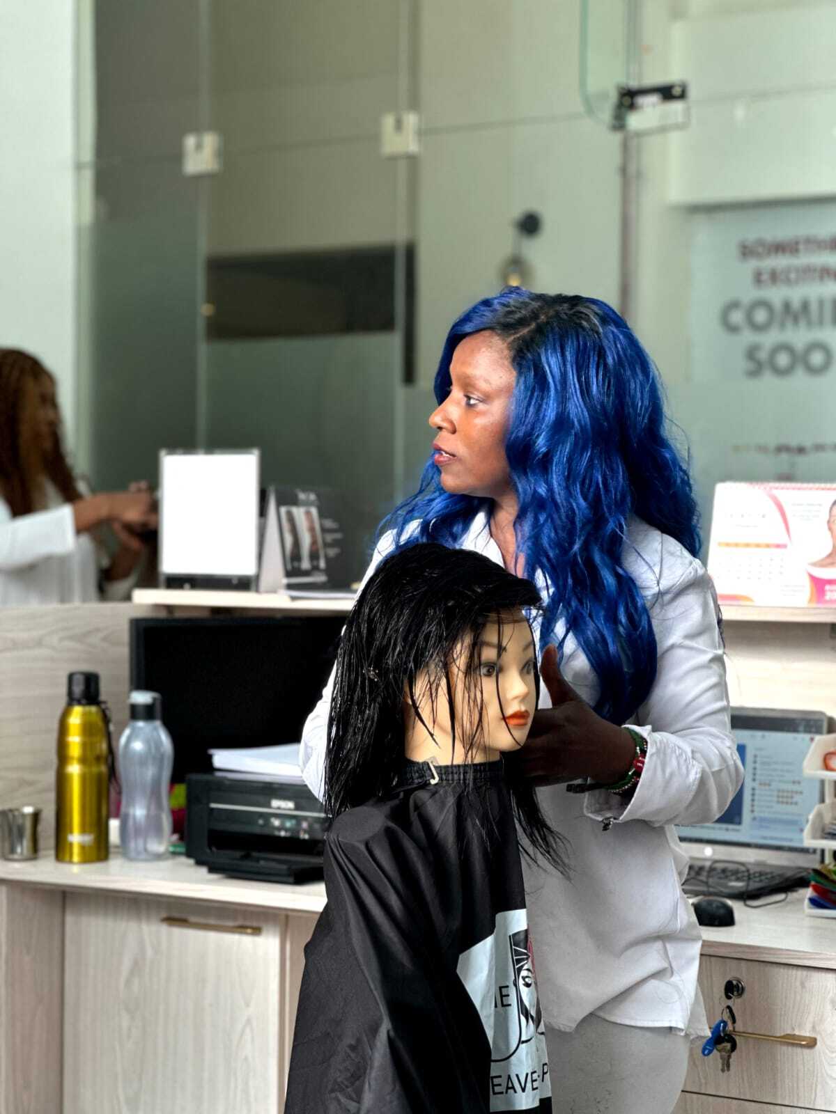 A student performing hair dressing on a dummy with real human hair