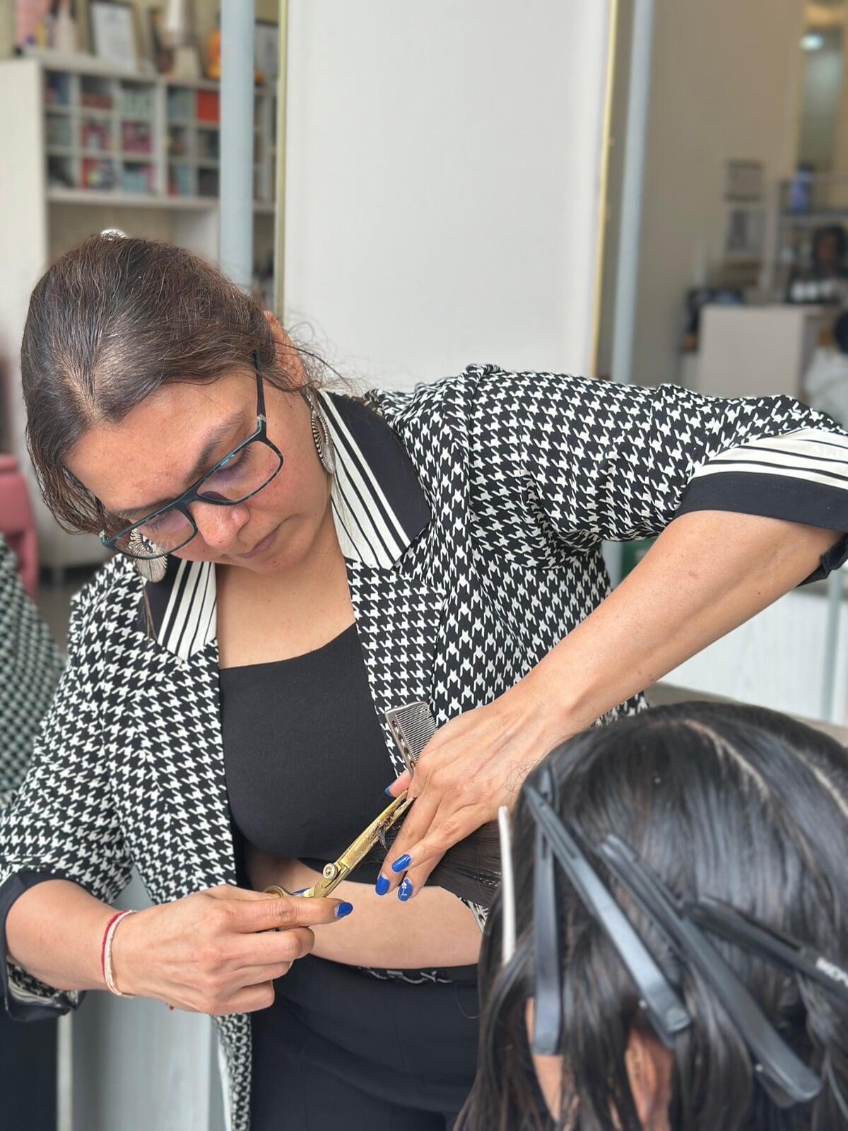 This picture shows Tejal, a professional hairdresser and the CEO of Tej's Beauty Cafe and Tej's cosmetology Training Institute, skilfully cut client's hair with her signature haircut style.